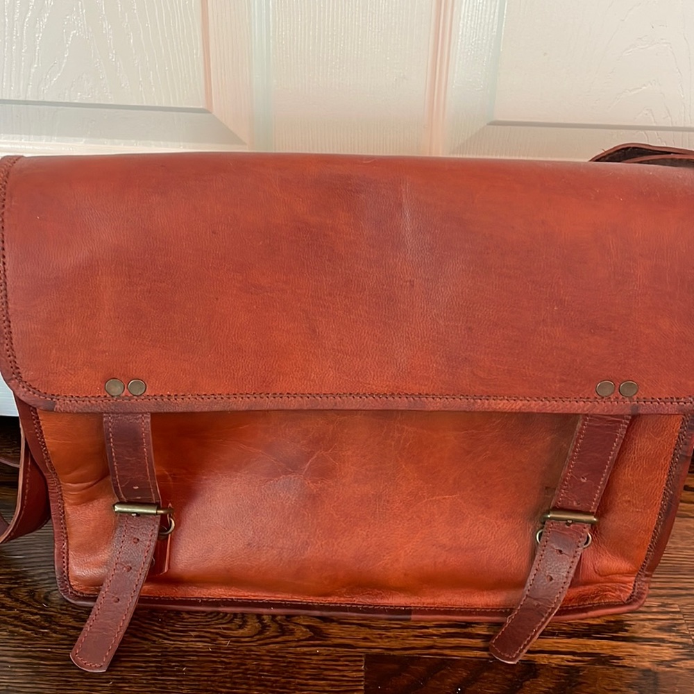 Genuine leather satchel. Inner zipper buckle closures on outside.
